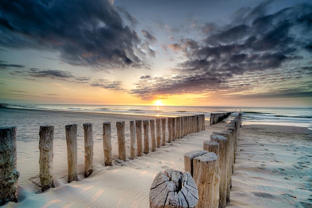 Free photo high angle shot of a wooden deck on the shore leading to the sea at sunset