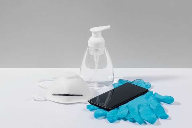 Free Photo high angle of smartphone on surface with surgical gloves and face mask