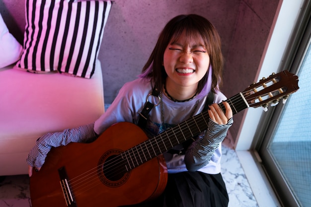 High angle smiley girl holding guitar