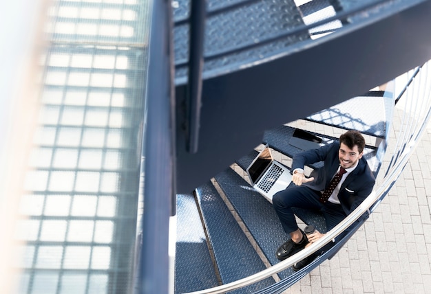 Free photo high angle smiley lawyer sitting on stairs