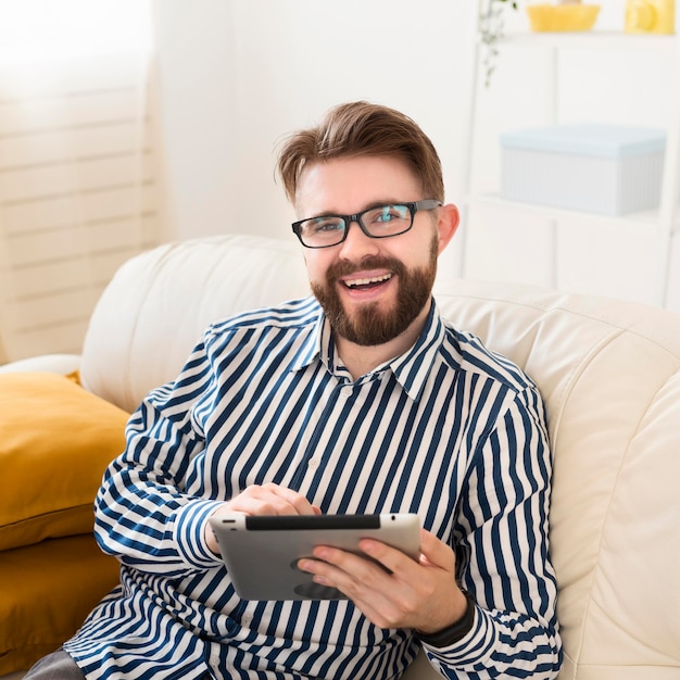 High angle of smiley man on sofa with tablet