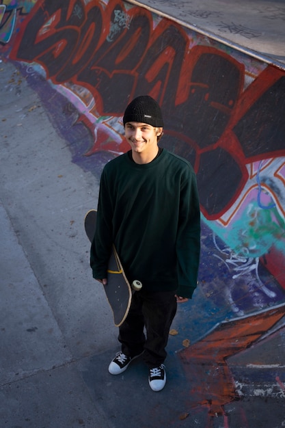 Free Photo high angle smiley teen holding skateboard