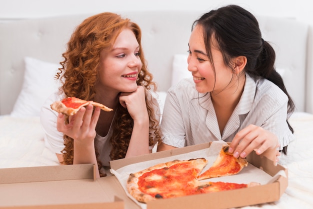 High angle smiley women eating pizza