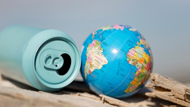 Free Photo high angle soda can beside small globe