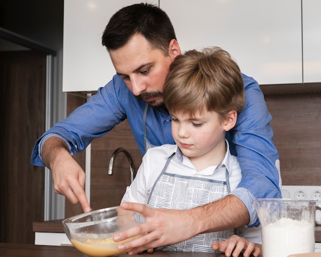 High angle son and father mixing eggs