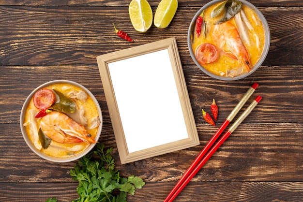 Free photo high angle soups in bowls with shrimp lemon and chopsticks with blank frame