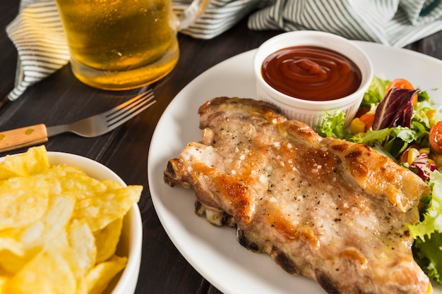 High angle of steak on plate with sauce and glass of beer