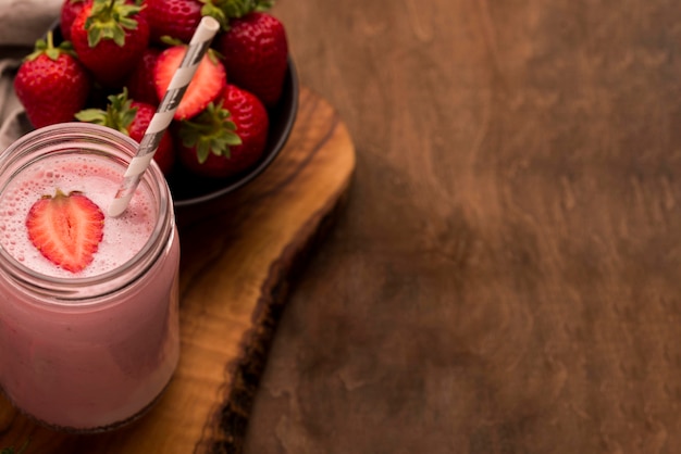 Free photo high angle of strawberry milkshake with straw and copy space