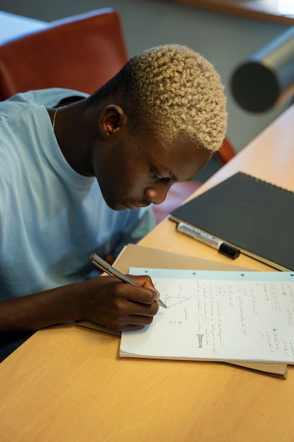 High angle student writing on notebook