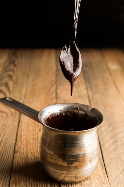 Free photo high angle teaspoon with melted chocolate over pot