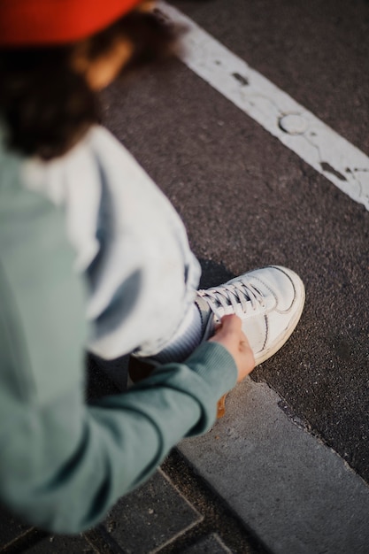 High angle of teenager tying shoelaces outdoors