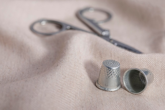 Free photo high angle of thimbles with scissors on textile