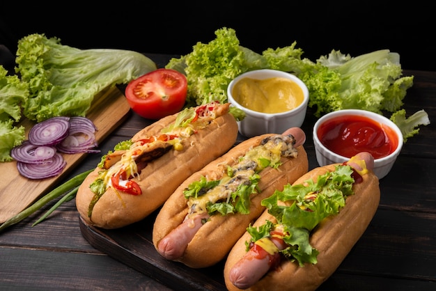 High angle of three hot dogs with salad and sauce