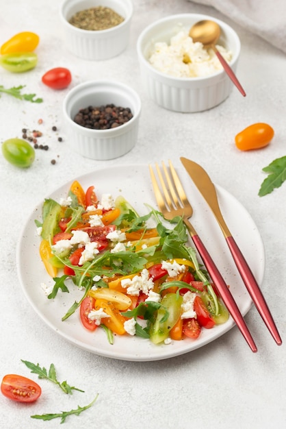 Free photo high angle tomato mix salad with feta cheese, rucola and cutlery