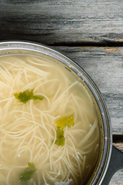 Free photo high angle vertical a homemade soup with spaghetti and greens on a wooden surface