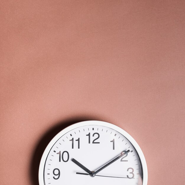 High angle view of an alarm clock on brown backdrop