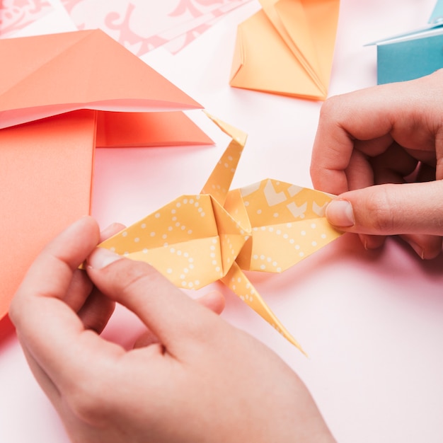 Free photo high angle view of artist hand holding origami paper bird