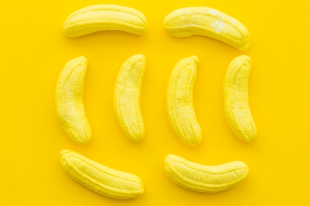 Free photo high angle view of banana shaped candies on yellow background