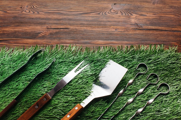 Free photo high angle view of barbecue utensil set on green mat over wooden table