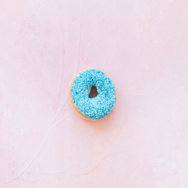 Free photo high angle view of blue donut on pink background