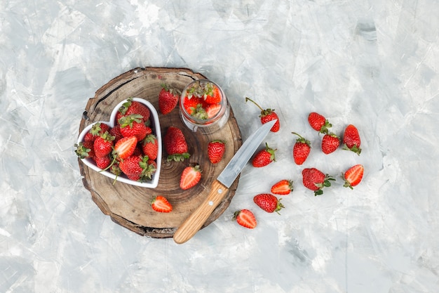 High angle view a bowl of strawberries on round wicker placemat on dark blue marble surface. horizontal