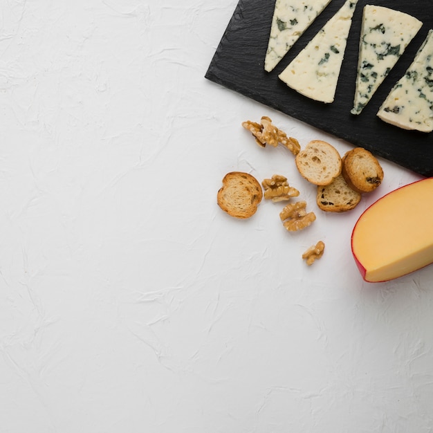 Free photo high angle view of bread slice and cheese pieces with walnut