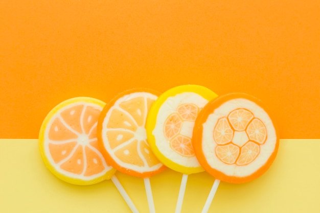 Free photo high angle view of citrus fruit candies on yellow and orange background