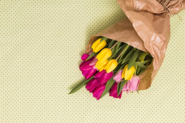 Free photo high angle view of colorful tulip flowers over yellow background