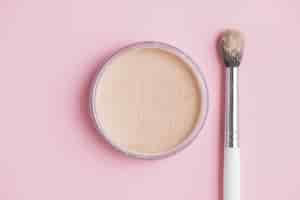 Free photo high angle view of compact powder and brush on pink backdrop