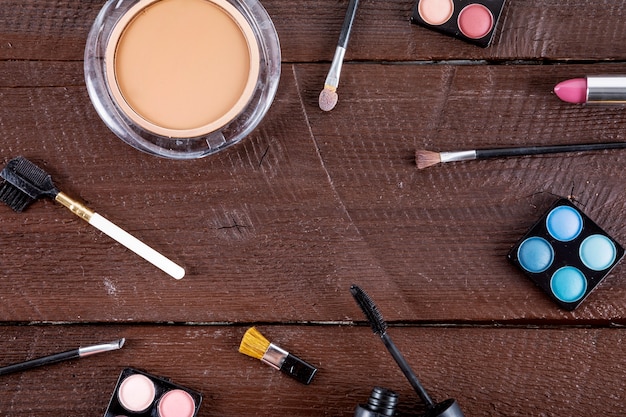 Free photo high angle view of cosmetic products with brushes on wooden background