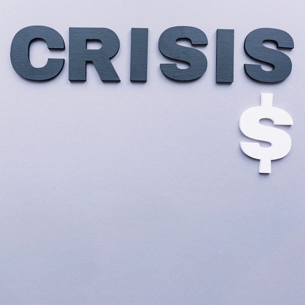 Free photo high angle view of crisis word with dollar sign on grey backdrop