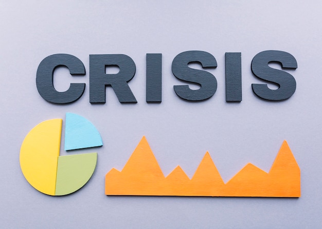 Free photo high angle view of crisis word with graphs on grey background