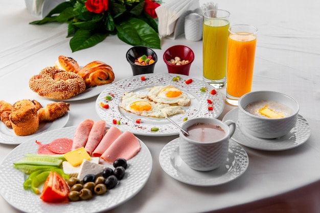 Free Photo high angle view delicious breakfast in table with salad, fried eggs and pastry on white background. horizontal