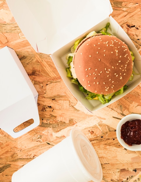 Free photo high angle view of delicious burger with disposal cup and food parcel