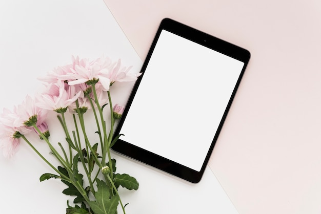 High angle view of digital tablet and bunch of flowers on dual background