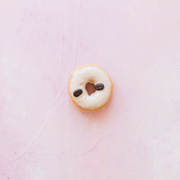 Free photo high angle view of donut decorated with coffee beans on pink background