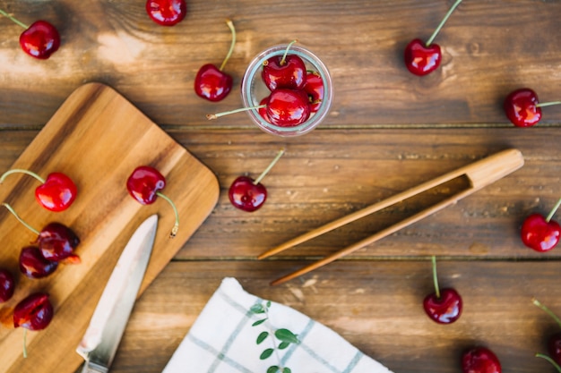 Free Photo high angle view of fresh ripe cherries and knife on cutting board