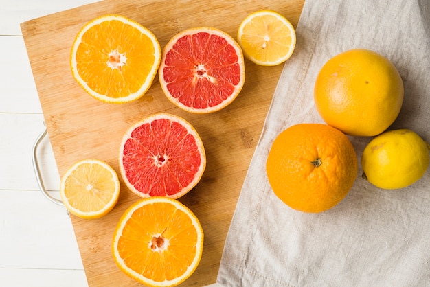 Free photo high angle view of halved citrus fruits on wooden chopping board