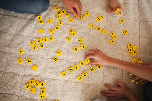 High angle view of hand playing scrabble game on carpet