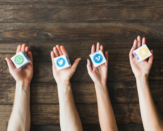 Free photo high angle view of hands holding boxes of vivid mobile application icons