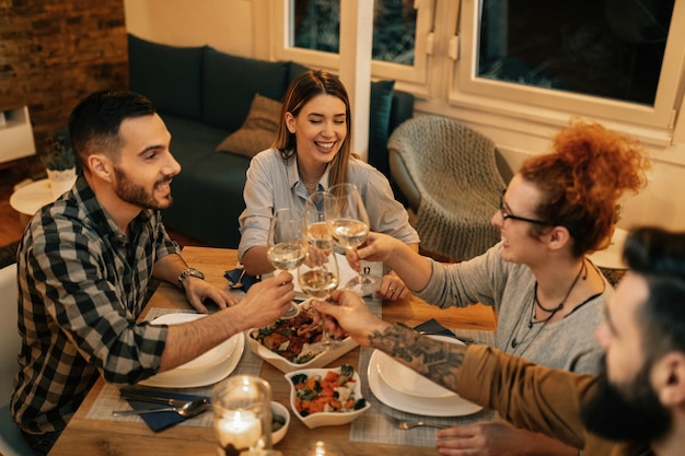 Free photo high angle view of happy friends toasting with wine while having dinner together