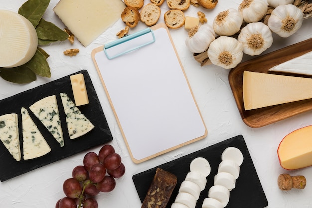 Free photo high angle view of healthy ingredient and various cheese with empty clipboard