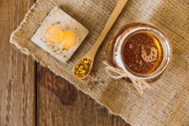 Free photo high angle view of honey; bee pollen seeds and candies on sack cloth