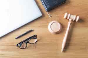 Free photo high angle view of laptop; spectacles; gavel and pen on wooden background on wooden desk