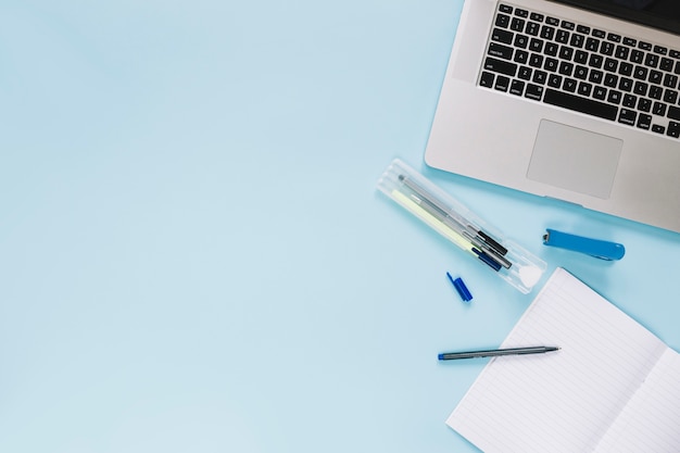 High angle view of laptop and stationeries on blue background