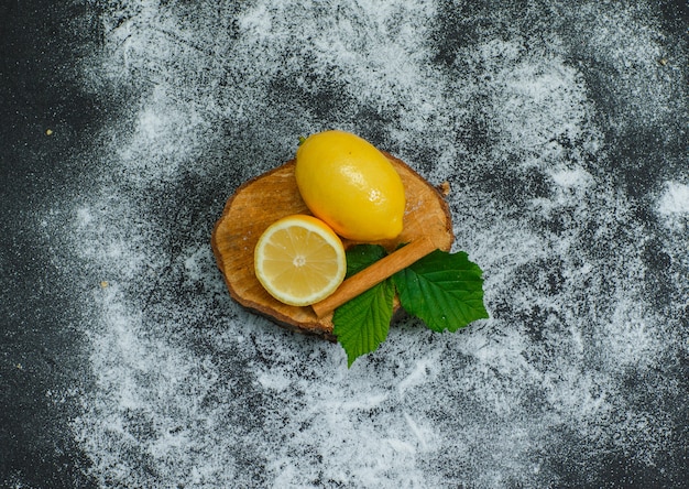 High angle view lemons with leaves and dry cinnamon on wood slice and dark. horizontal