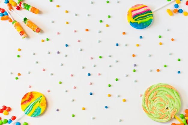 Free photo high angle view of lollipops and candies on white background