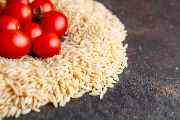 Free photo high angle view macaroni with tomatoes on them on dark textured background. horizontal