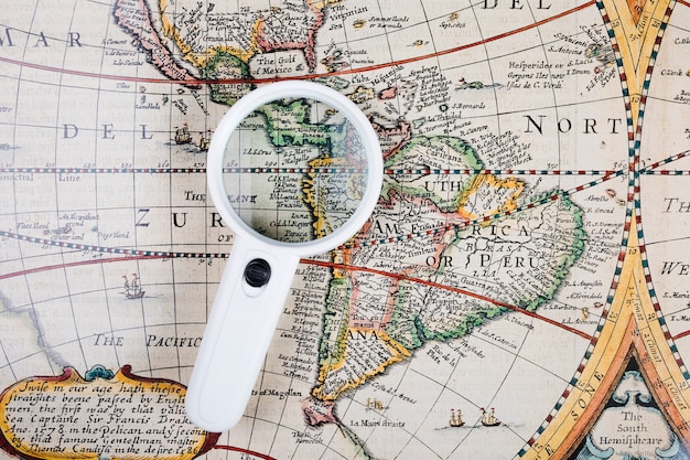 Free photo high angle view of magnifying glass on old world map