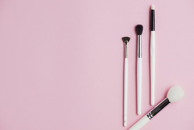 High angle view of makeup brushes on pink background